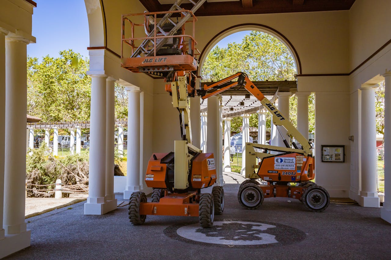 our-mission Construction lifts under architectural arches, showcasing urban renovation efforts.