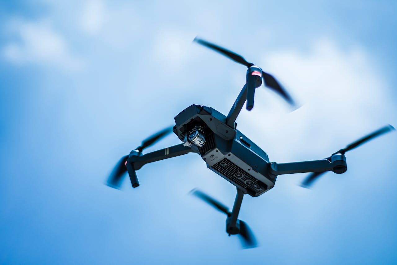 services-03 A sleek drone captures the sky in action with a clear blue background, showcasing modern technology.